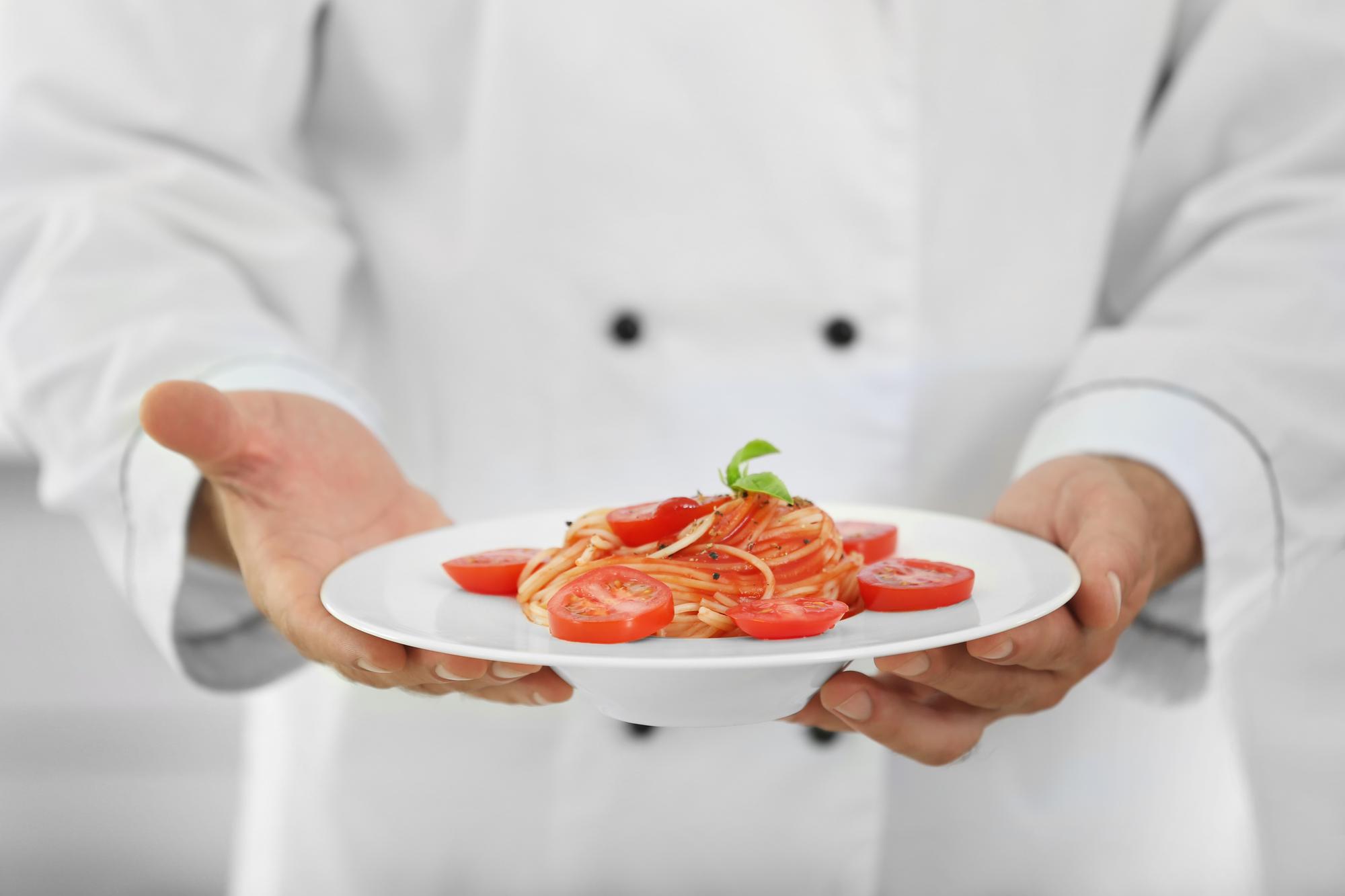 Chef hands plating a dish in studio